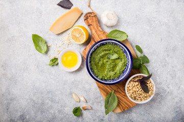fresh Green basil pesto with italian recipe ingredients over light table copy space for text overhead