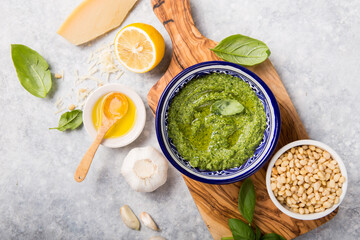 fresh Green basil pesto with italian recipe ingredients over light table copy space for text overhead