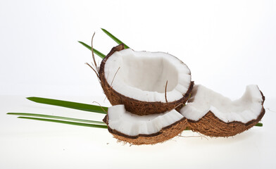 Coconut pieces with palm leaves isolated on a white background.