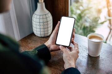 cell phone mockup image blank white screen.woman hand holding texting using mobile on desk at coffee shop.background empty space for advertise.work people contact marketing business,technology