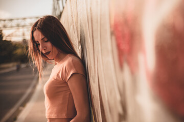 Ragazza bella e carina posa con grazia ed eleganza nei suoi vestiti estivi durante una sessione fotografica all'aperto in una località estiva al tramonto