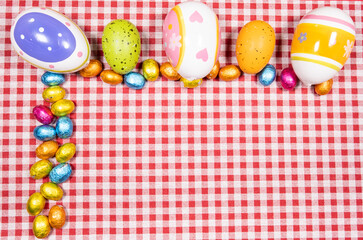 Mix of easter eggs of all colors and sizes on a background of red and white gingham fabric. Easter concept