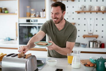 Handsome man preparing breakfast at home. Young man drinking coffee in kitchen.	