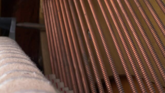 super close up. details of bass strings and hammers inside the piano