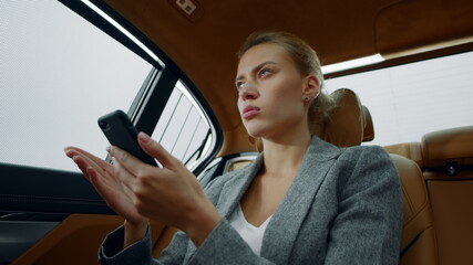 Portrait of woman typing letter on phone at luxury car. Girl thinking at vehicle