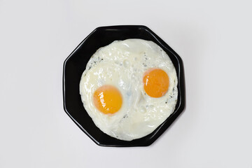 Close up of two delicious fried eggs on a plate ready to eat isolated on a white background