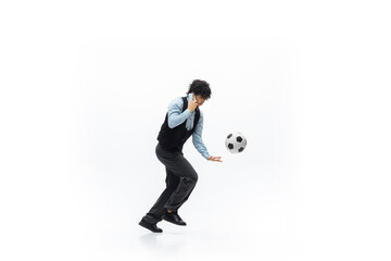 Man in office clothes playing football or soccer with ball on white background like professional player. Unusual look for businessman in motion, action kicking ball. Sport, healthy lifestyle