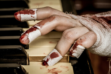 A bandaged bloody hand plays the piano
