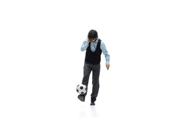 Man in office clothes playing football or soccer with ball on white background like professional player. Unusual look for businessman in motion, action kicking ball. Sport, healthy lifestyle