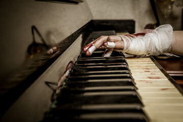A bandaged bloody hand plays the piano - 365258141