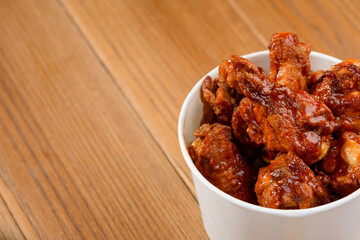Paper bucket of chicken drumsticks on wooden background