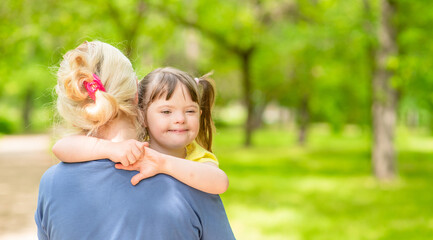 Woman holds in her arms a happy daughter with down syndrome. Empty space for text