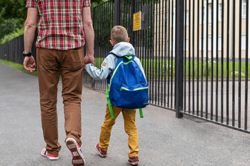 Way to school. Dad leads his young son by the hand to school. Back to school.