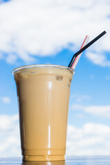 a iced coffee in takeaway cup in the background of blue sky