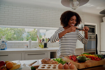 Side video of young successful female food blogger taking picture of freshly slices and chopped vegetables in modern kitchen