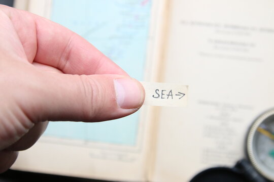 A pointer to the sea against the backdrop of a tourist atlas. Summer tourism idea.