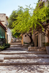 Fototapeta na wymiar Picturesque quiet alley in the Plaka old town of Athens with steps, trees and flowers.