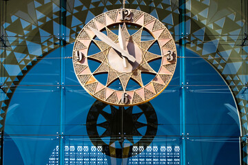 Isolated old metal wall clock with its shadow on a glass building