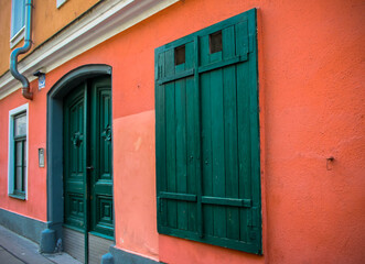 Old green closed shutters and entrance door on an orange buiding