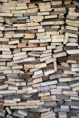 A large pile of cut wooden boards arranged along a wall