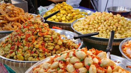 Exotic Oriental Asian sweet delicious desserts, unusual colorful traditional dishes on the counters of a bazar with street food. Evening food court in bangkok, the capital of cooking. Night market.