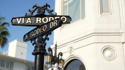 Fototapeta na wymiar World famous Rodeo Drive symbol, Cross Street Sign, Intersection in Beverly Hills. Touristic Los Angeles, California, USA. Rich wealthy life consumerism, Luxury brands and high-class stores concept.