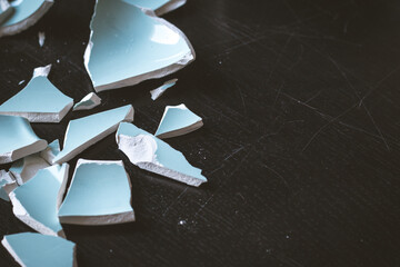 Light blue shards of a broken vase on a black table
