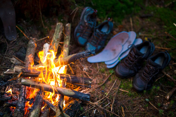 Hiking boots are drying near the fire in the forest