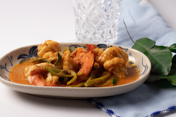 Stir fried shrimp with curry paste in a white plate.