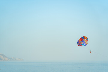 Fototapeta na wymiar paragliding couple doing extreme sport in the middle of the ocean with beautiful blue sky