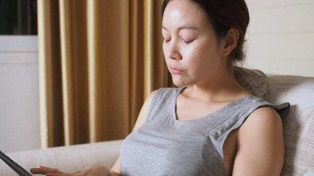 asian woman working from home with tablet and got neck pain in living room.