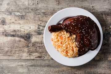 Traditional mole Poblano with rice in plate on wooden table. Top view. Copy space - obrazy, fototapety, plakaty