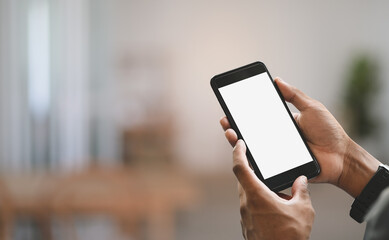 Cropped image businessman's hands are using a white blank screen smartphone over blurred background.