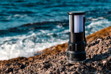 solar powered camp lamp on the rocks with view of clear blue sea  