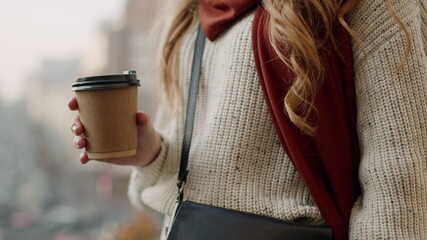 Beautiful girl having coffee outdoors. Hipster woman sipping tea on street.