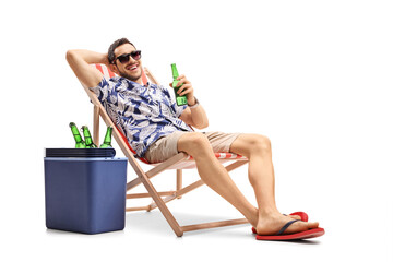 Tourist with a bottle of beer on a deckchair with a cooling box beside him - obrazy, fototapety, plakaty