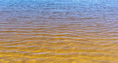 Natural gradient from blue to yellow. Ripples on the surface of the water.