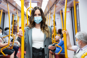 Enterprising young woman wearing a face mask travelling on public transport during rush hour....