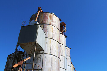 looking up at a rusty old working agricultural feed grain and corn silo building against a blue sky in rural heartland america perfect for industry farming and commercial agriculture marketing