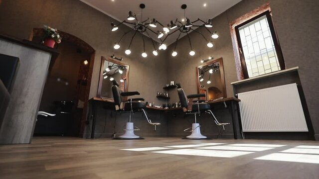 Hair salon interior. Empty chairs in styled barbershop. Barbershop room with two working places in the beauty salon. Chairs and mirrors in modern hairdressing. Interior of a modern hair salon