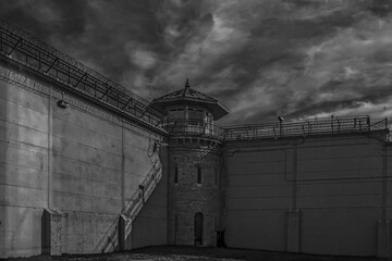 Kingston Penitentiary at night inside prison yard moonlight high stone walls barbed wire and guard tower nobody