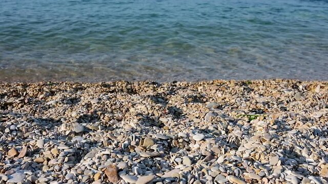 Light waves of the Adriatic sea crashing at the sunset on the shore of the pebbly beach of Conero in the marche region in italy