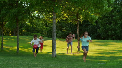Children with parents running in summer park. Joyful family playing in meadow