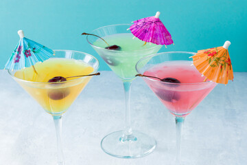 Glasses of various delicious fruit non-alcoholic cocktails on a bright background with umbrellas and cherries. Health drinks