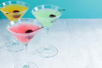 Glasses of various delicious fruit non-alcoholic cocktails on a bright background with cherries. Health drinks.