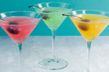 Glasses of various delicious fruit non-alcoholic cocktails on a bright background with cherries. Health drinks