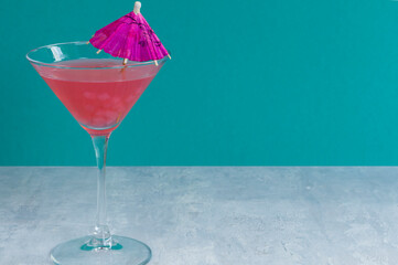 Glass of delicious fruit non-alcoholic cocktail on a bright background with an umbrella. Health drinks.