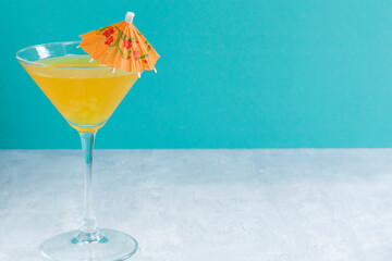 Glass of delicious fruit non-alcoholic cocktail on a bright background with an umbrella. Health drinks.