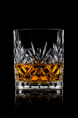 Scotch whiskey in crystal elegant glass on black background.