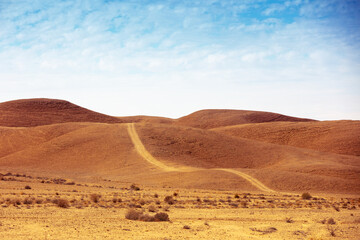 Desert landscape with blue sky. Dirt road in mountains